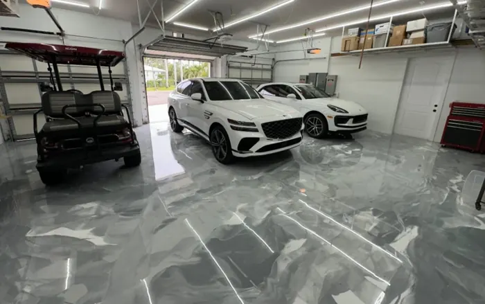 Silver and gray metallic epoxy garage floor with parked SUVs and golf cart